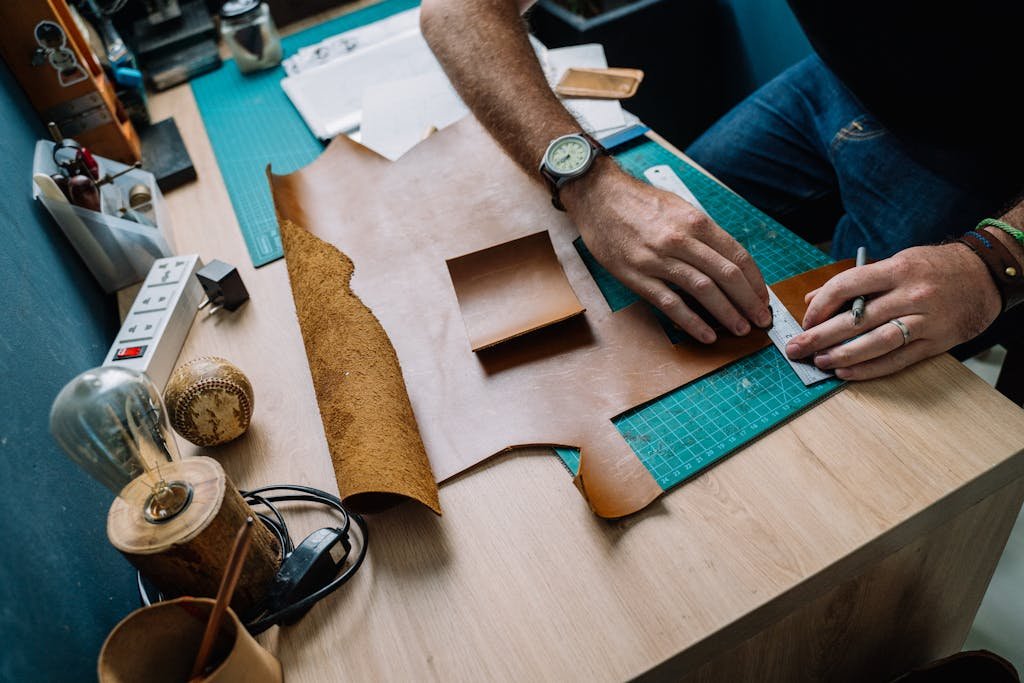Close-up of hands cutting leather in a creative artisan workspace, showcasing craftsmanship skills.